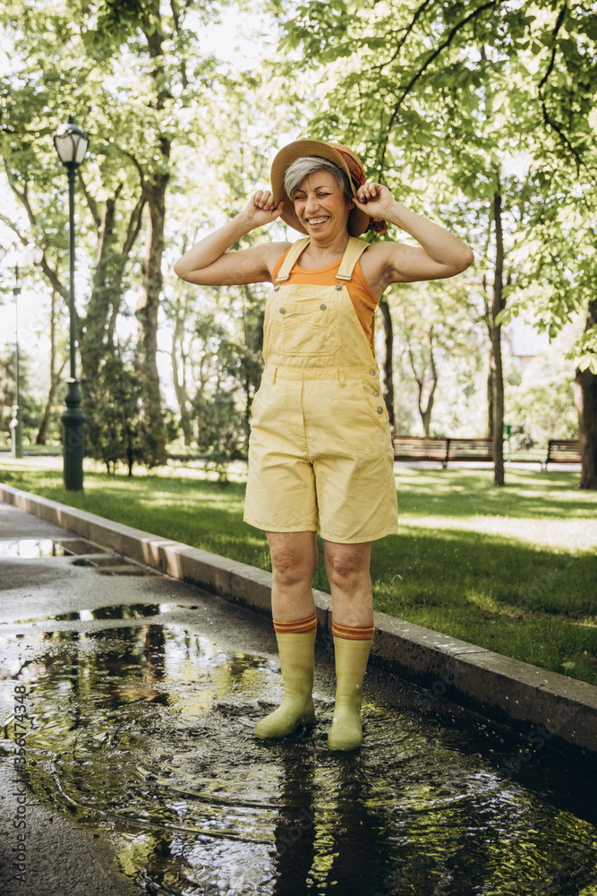 Elderly woman dressed in yellow is having fun in the park Elderly woman dressed in yellow is having fun in the park