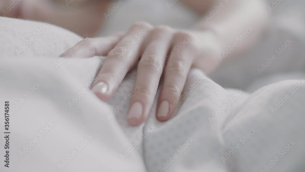 Woman's hand gently stroking the bed sheets Woman's hand gently stroking the bed sheets