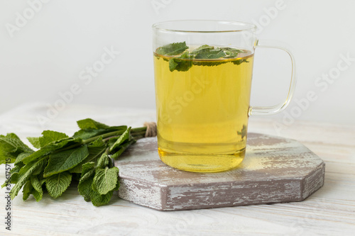 Mint tea, transparent cup with mint tea on a wooden table