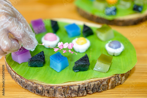 Thai Chef's hand is decorating Varieties traditional colorful Thai desserts set; steaming flour, black custard, coconut custard & steaming bean, layer pudding cake photo