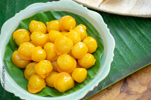 Kanom Thongyip and Thongyhod, egg yoke fudge balls cooked in syrup on banana leaf from topview in the small dish ready to serve for dessert. photo