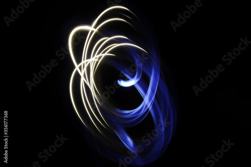 Abstract blue and white light painting photography, long exposure photo of dual tone fairy lights in a loop against a black background.