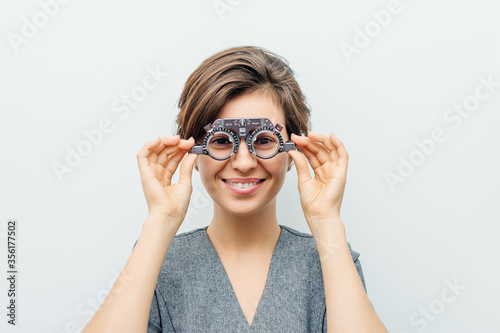 Принти на полотні smiling woman in optical trial frame on light gray background