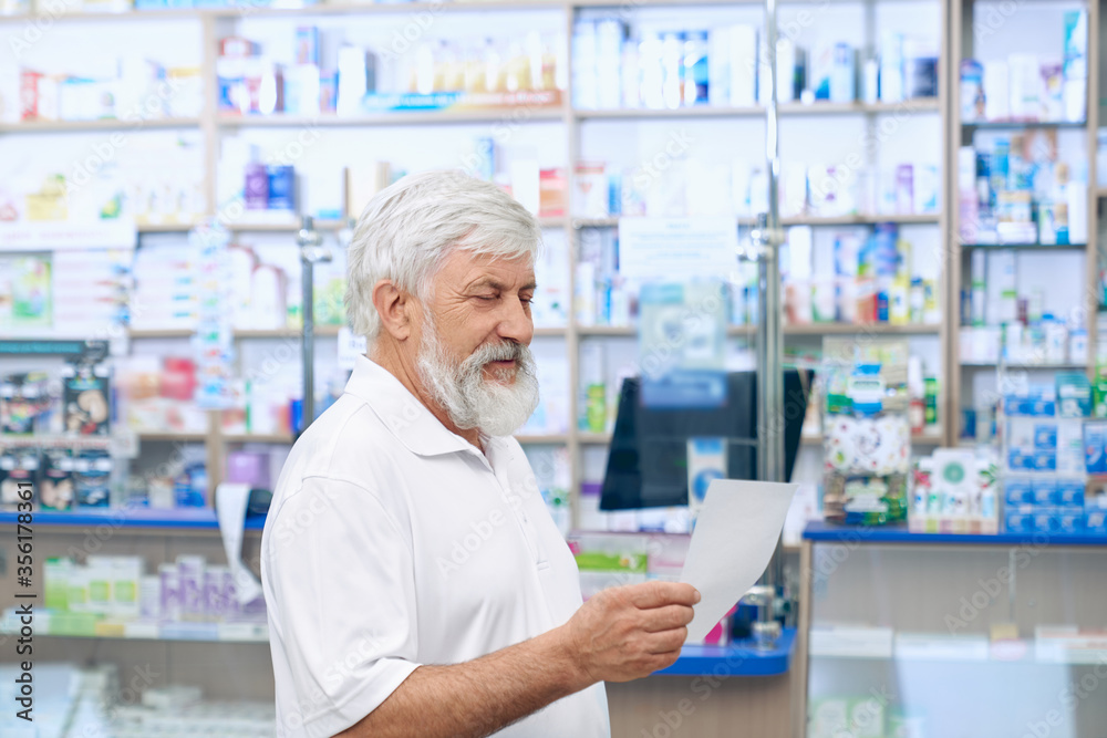 Senior man reading prescription in apothecary.