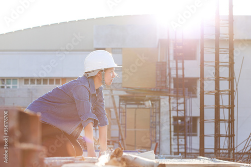 Female Engineer looking at steel wire binding work. Forewoman inspect constructing area in the afternoon. Engneering woman kneeling on the blueprint. Wearing helmet  for safety. photo