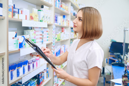 Female pharmacist with folder examinating medicaments. photo