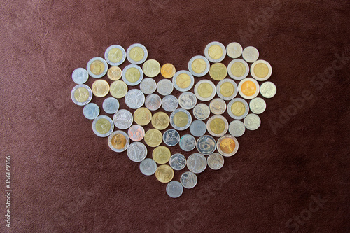 Heart shape made from coins on dark brown flannel . Valentines concept.