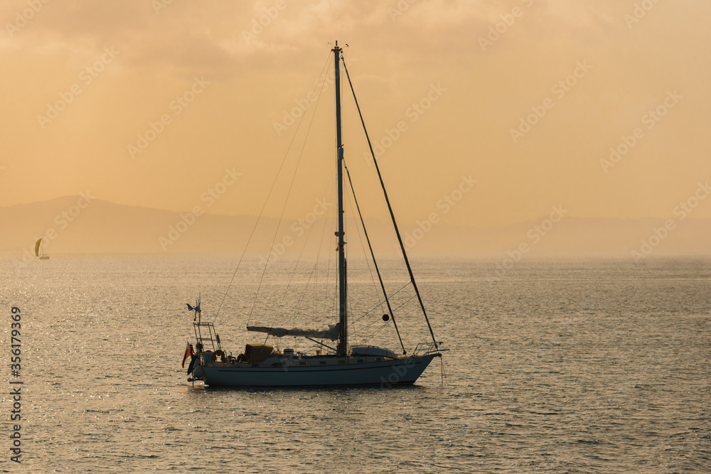 sailing yacht against sunset tinted in warm tones sailing yacht against sunset tinted in warm tones