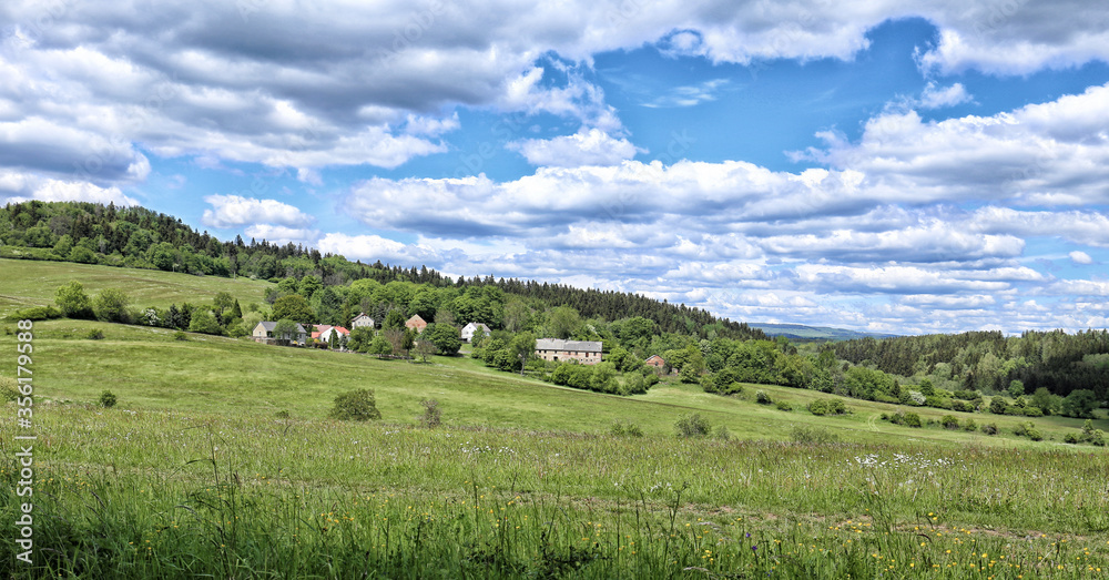 Small village with few houses on hillside with cloudy sky