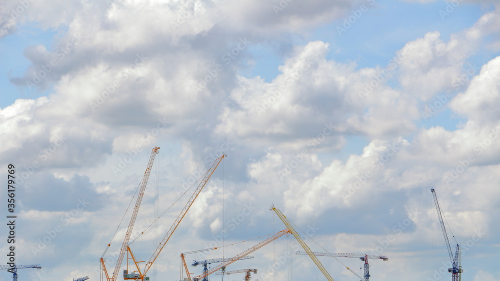 Fototapeta premium The industrial building crane behind the blue sky and white clouds