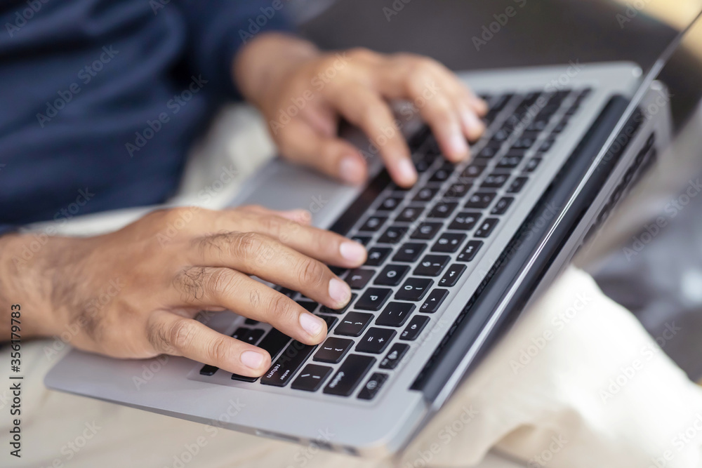 lifestyle man close up hand keyboard sit work on sofa using a laptop computer to work home and search information social network online. lifestyle man close up hand keyboard sit work on sofa using a laptop computer to work home and search information social network online.