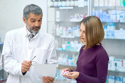 Pharmacist explaining instruction of pills to woman.