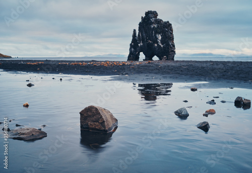 A huge black rock on the shore at low tide. Hvitserkur, Iceland. photo