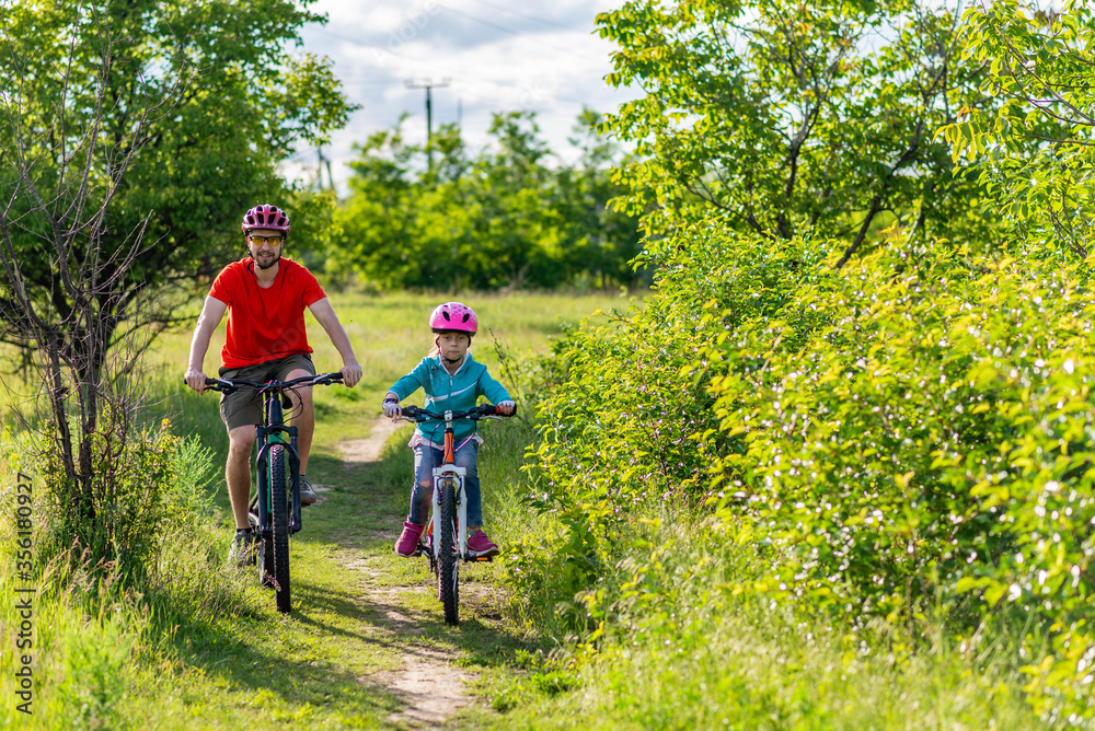 Dad and daughter ride bikes along the path, an active lifestyle. Dad and daughter ride bikes along the path, an active lifestyle.
