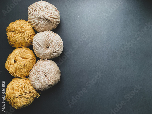 Mustard and beige yarn for knitting on a black background. Needlework, crocheting, Hobbies.