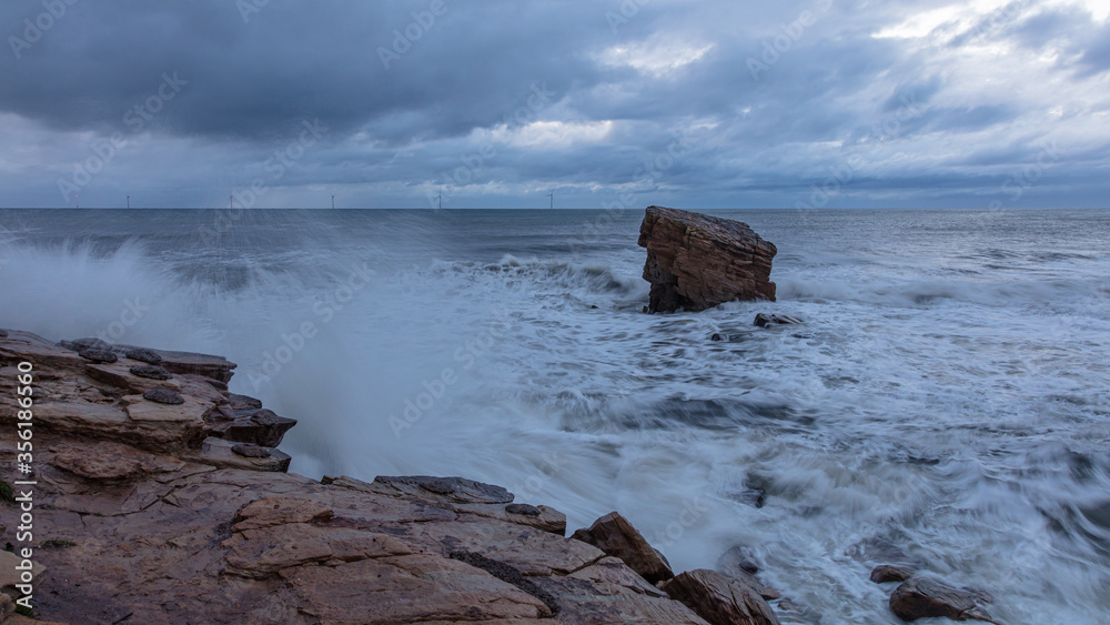 Rough Sea and brooding, stormy sky over Charlies Garden, rock pillar at Seaton Sluice on the coast of Northumberland, England, UK. Rough Sea and brooding, stormy sky over Charlies Garden, rock pillar at Seaton Sluice on the coast of Northumberland, England, UK.