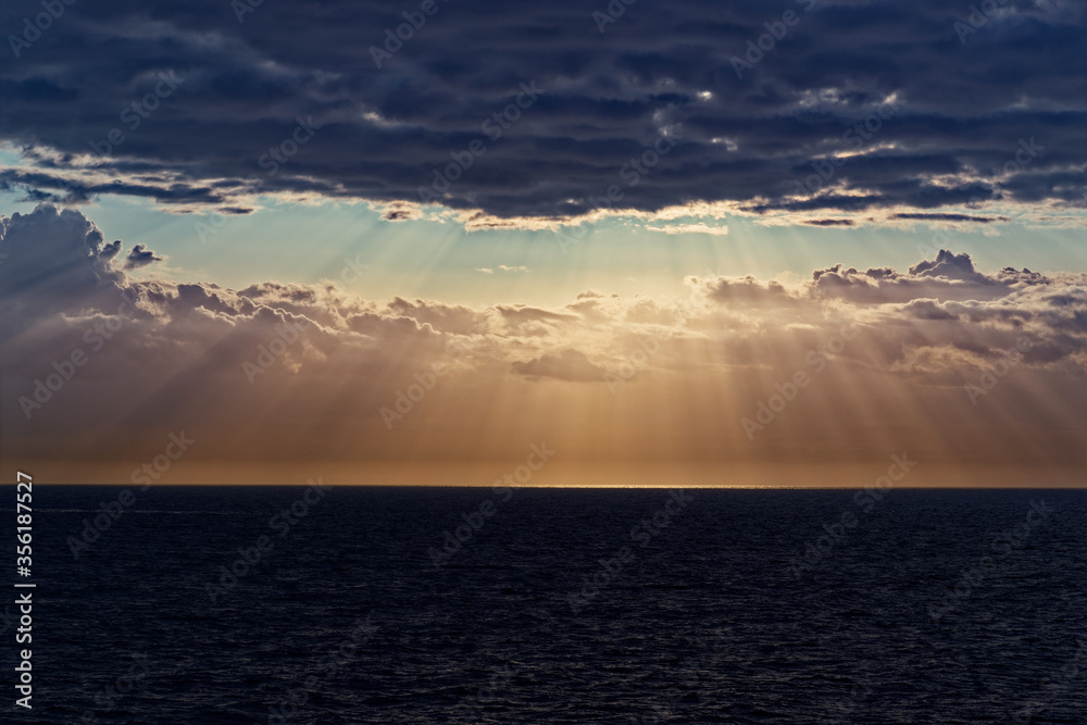 Sunbeams and dark clouds over sea during sunset Sunbeams and dark clouds over sea during sunset
