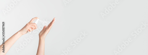 Closeup view of young female spraying antiseptic onto her hands against white background, copy space photo