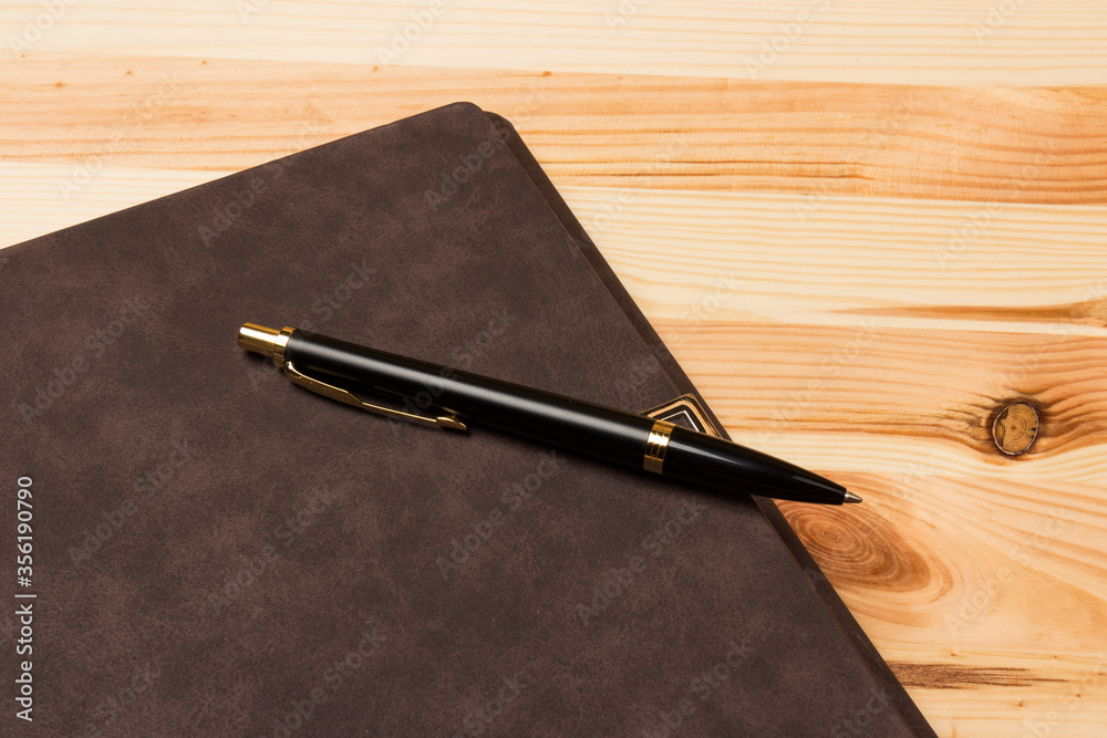 Leather-bound business notebook with a Parker pen on wooden background. Business concept Leather-bound business notebook with a Parker pen on wooden background. Business concept