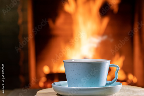 A cup of Tea before burning fireplace in a country house.