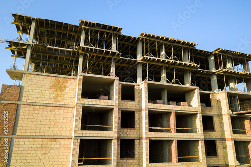High multi storey residential apartment building under construction. Concrete and brick framing of high rise housing. Real estate development in urban area.