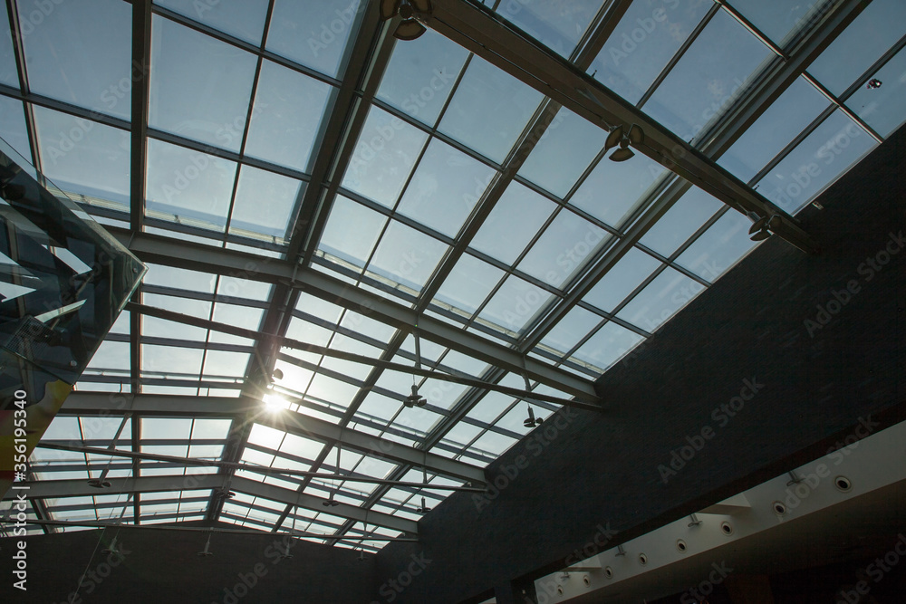 The glass roof of a modern house through which the bright sun shines