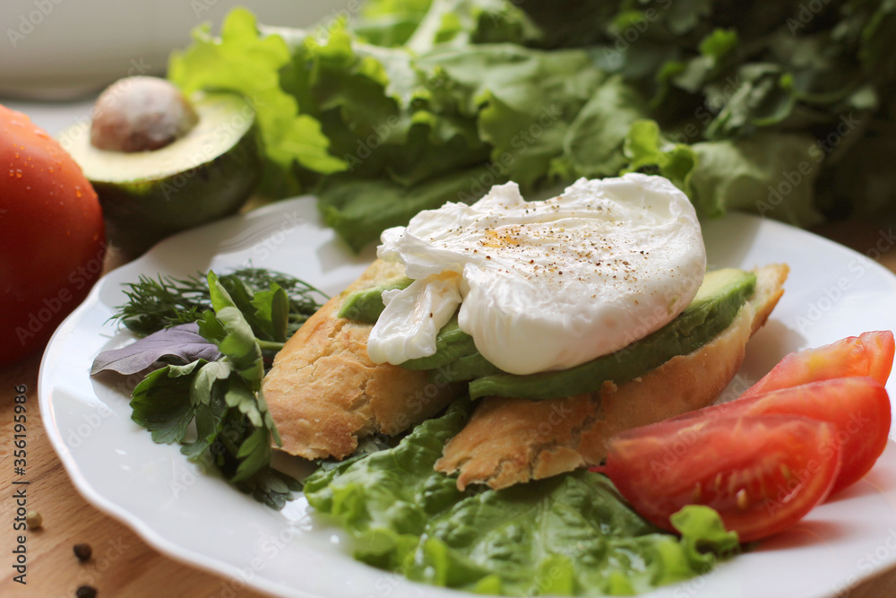 Healthy fresh food on a white plate whith poached egg avocado tomato bread and salad