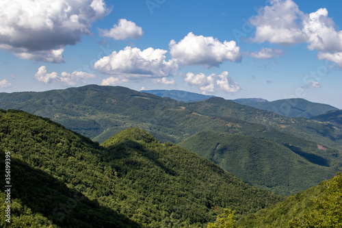 Green mountain with trees and clouds in a blue sky. Italian Appennini mountain