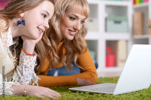 Close up portrait of young woman with girl using laptop photo