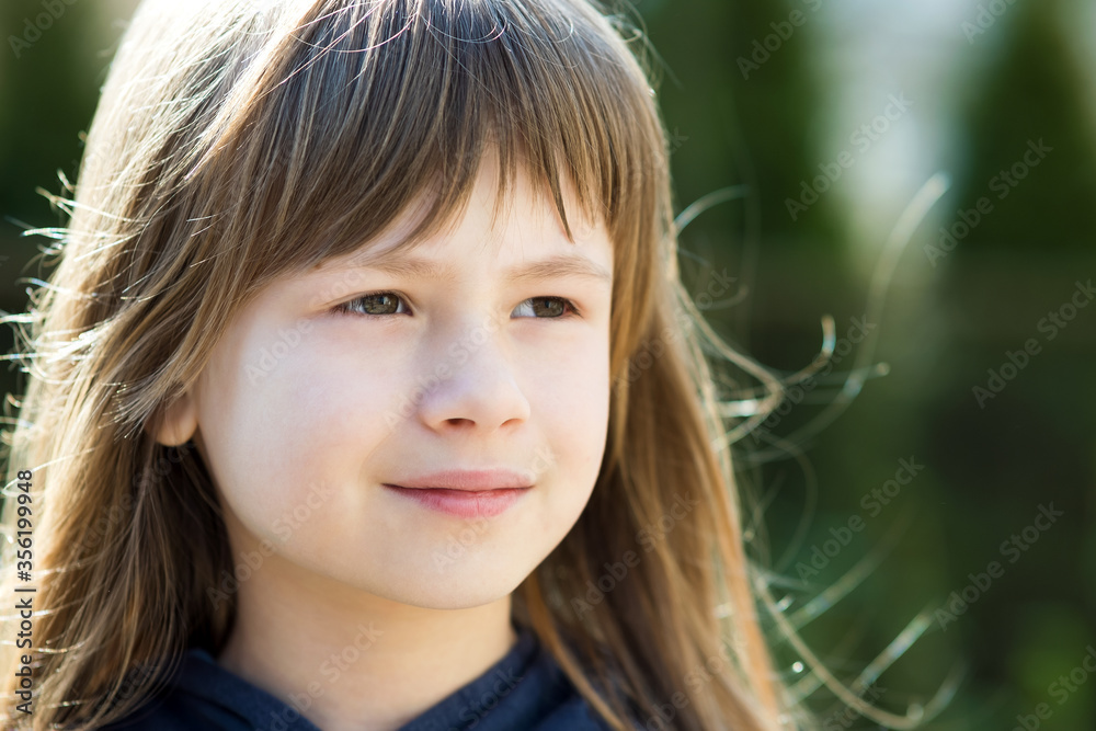 Portrait of pretty child girl with gray eyes and long fair hair outdoors on blurred bright background. Cute female kid on warm summer day outside.