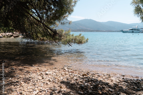 Fototapeta Naklejka Na Ścianę i Meble -  Love Bay on Poros island, Greece. Summer beach with blue sea and white yacht.