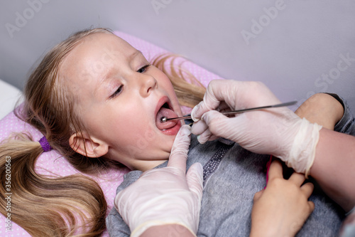 Little girl in class with a speech therapist . The use of special tools for speech correction.