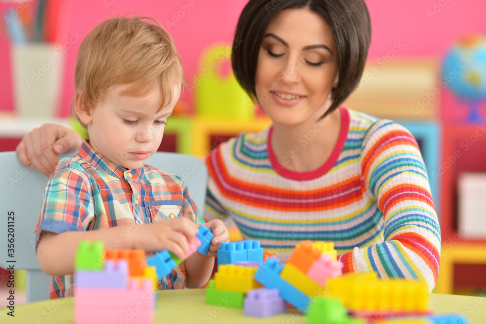 Young mother and cute little son playing with colorful plastic blocks Young mother and cute little son playing with colorful plastic blocks