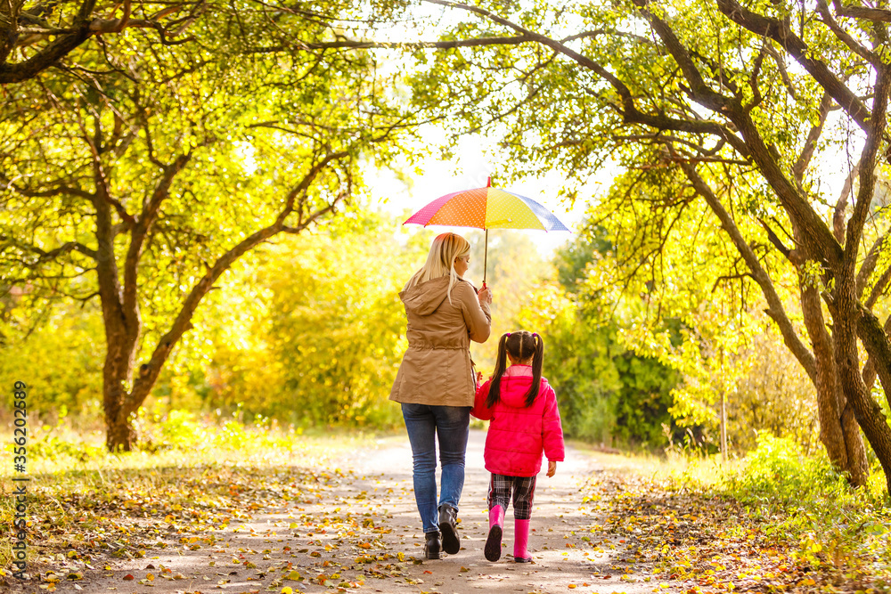 Young mother and her little daughter outdoors in colorful raincoats Young mother and her little daughter outdoors in colorful raincoats