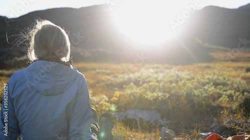 MS PAN Woman sitting in meadow and looking at sunset / South Greenland, Greenland