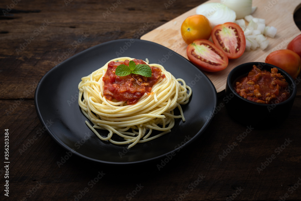 Fototapeta premium Italian pasta spaghetti with tomato sauce and herbs on a black plate a plate on dark woonen background with copy space for your text