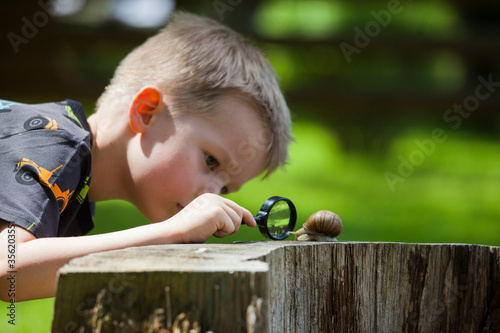 Young boy looking at snail through hand magnifier