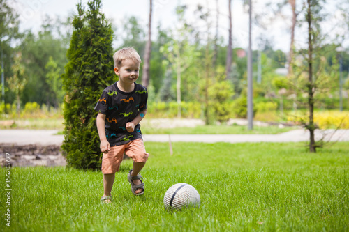 Little boy playing football in park.