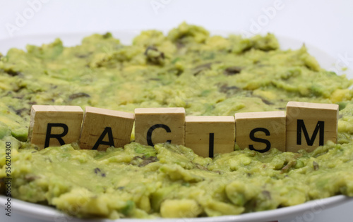 Close up of isolated word racism spelled by wooden letters on disgusting green slimy stodge (focus on word center)