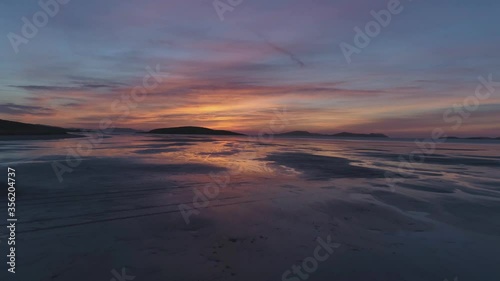 Isle of Barra, Scotland. Outer Hebrides. Scotland. Epic aerial drone video of sunset of the Isle of Barra airport with reflection in the water
