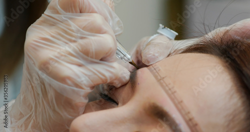 Woman undergo micro pigmentation eyebrows in a beauty salon
