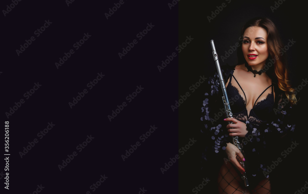 Female girl artist in suit with flute on black background. Flute in hand. Player with orchestra music instrument. Isolated on black. Author's space. Large background space for an inscription or logo