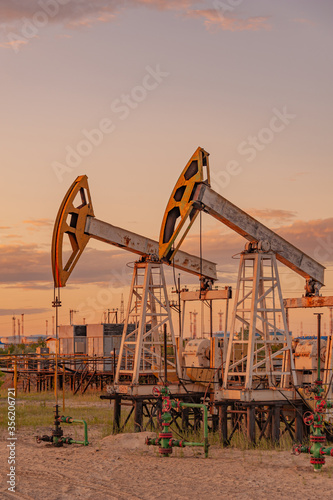 Petroleum concept. Oil pump rig. Oil and gas production. Oilfield site. Pump Jack are running. Drilling derricks for fossil fuels output and crude oil production. Global crisis. War on oil prices.