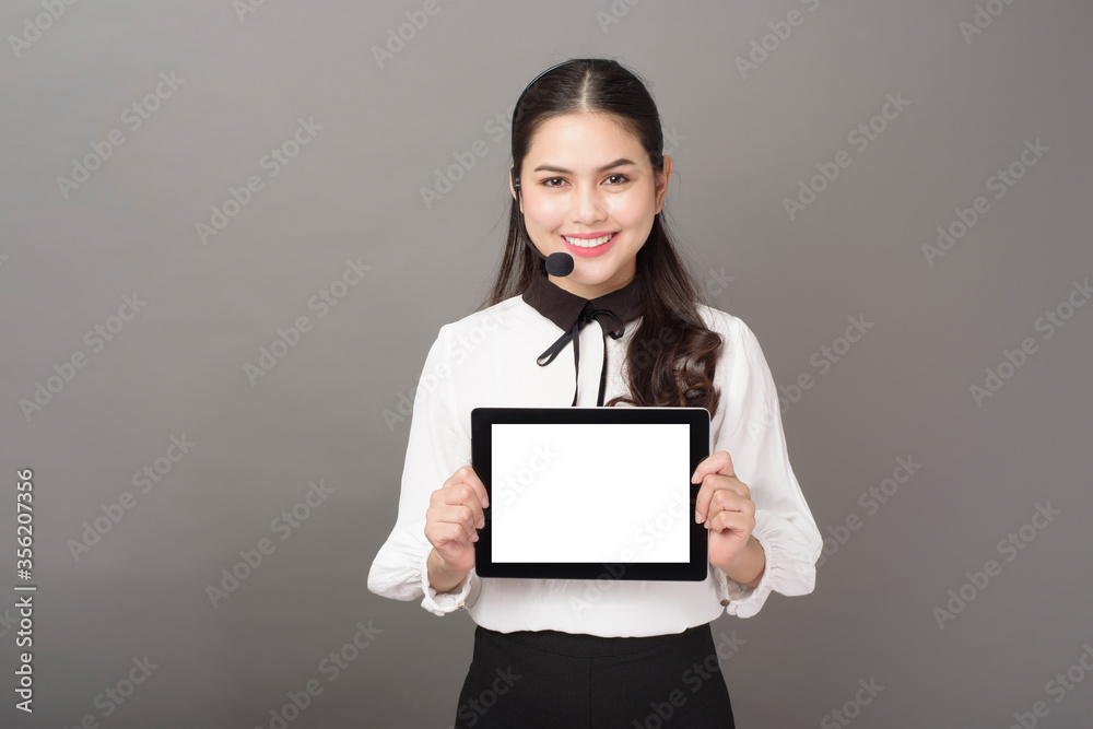 Portrait of beautiful operator woman on gray background with tablet mockup Portrait of beautiful operator woman on gray background with tablet mockup