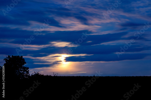 Night landscape with a bright moon in the cloudy sky