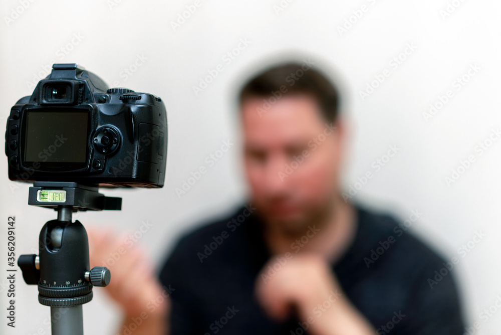 Influencer man sharing online review using dslr camera on tripod vlogger starts filming video.White background.