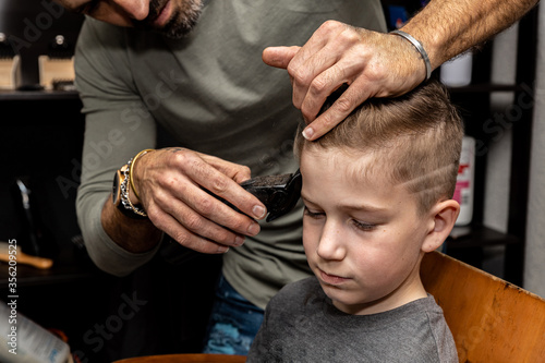 Hairdresser cuts the hair of a boy in a barbershop