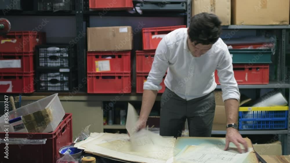 MS Man looking at blueprints in warehouse / Milan, Milan, Italy MS Man looking at blueprints in warehouse / Milan, Milan, Italy