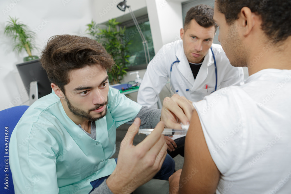junior doctor being supervised administering injection junior doctor being supervised administering injection