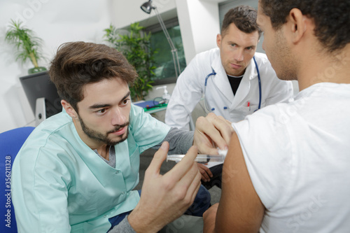 junior doctor being supervised administering injection